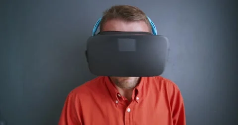 Close-up. Man in red shirt in virtual reality goggles and blue headphones. Stock Footage 172814661