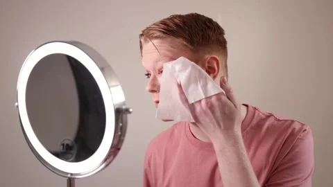 A Close-Up of a Man Removing Makeup with Wipe in Front of Mirror Stock Footage 310142466