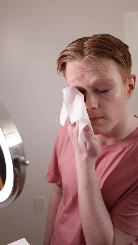A Close-up of a Man Removing Makeup with Wipe in Front of Mirror Stock Footage 310223617
