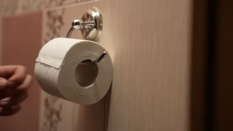 Close-up of man replacing empty toilet paper roll with new white roll Stock Footage 325802243