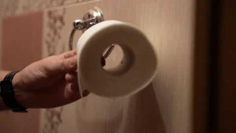Close-up of man replacing empty toilet paper roll with new white roll Stock Footage 325802246