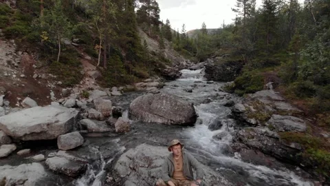 A close up of a man resting in the middle of raging stream in a mountain valley Stock Footage 164251142