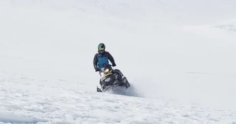 Close. Man rides a snowmobile on one runner down the snowy mountain slope Stock Footage 145251405