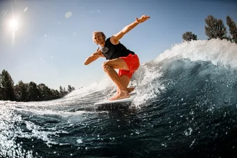 Close-up of man riding down the wave on surf style wakeboard on sunny day Stock-Fotos