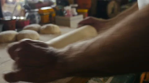 Close up of a man rolling out a pizza dough ball on a wooden cutting board Video stock 62837892