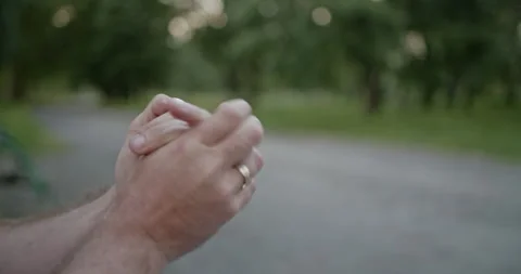 Close up of man rubbing hands together in outdoor setting, focus on hands. Stock Footage 280319366