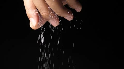 Close up of a man s hand letting salt fall on the food on a black background Stock Footage 160555749