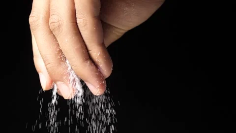 Close up on a man s hand sprinkling salt on the food with a black background Stock Footage 160556035