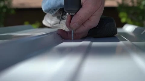 Close up of a man screwing down steel roofing on a building Stock Footage 277546378