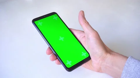 Close-up. man scrolls through green chromakey screen, holding his thumb on Stock Footage 166909499