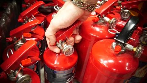 Close-up of a man selecting a red fire extinguisher from a store shelf Stock Footage 345699719
