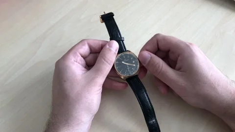 Close-up. A man sets the correct time on a vintage gold wristwatch with a black Stock Footage 136956020