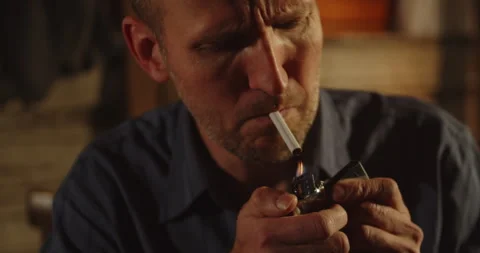 Close up of a man in a shady hide grabbing a cigarette and lighting it Stock Footage 327273304