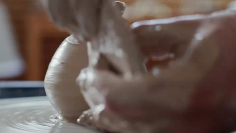 Close up of man shaping clay vase on spinning wheel during work in pottery Stock Footage 143615426