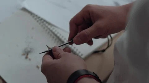 Close-Up: Man Sharpening Knife Black Pencil, on the Background of Copybook Video stock 76347685