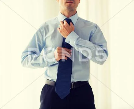 Close Up Of Man In Shirt Adjusting Tie On Neck
