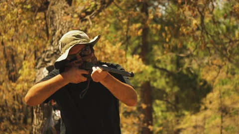 Close up of a man shooting a bb gun and reloading while shooting cans in a Stock Footage 160707000