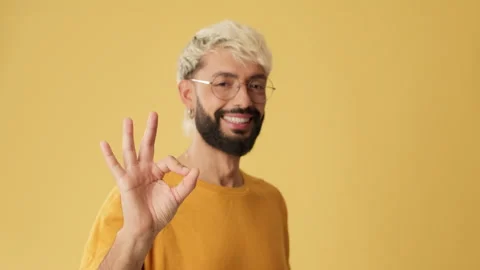 Close up, man showing ok gesture, looking at camera isolated on yellow Stock Footage 254914383
