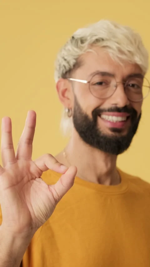 Close up, man showing ok gesture, looking at camera isolated on yellow Stock Footage 254914479