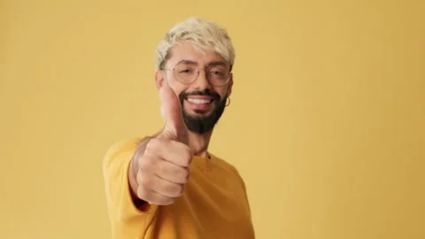 Close up, man showing thumbs up gesture, looking at camera isolated on yellow Video stock 253934113