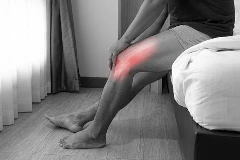 Close up a man siting on the bed and holding his knee pain Joint pain, Arthri Stock Photos