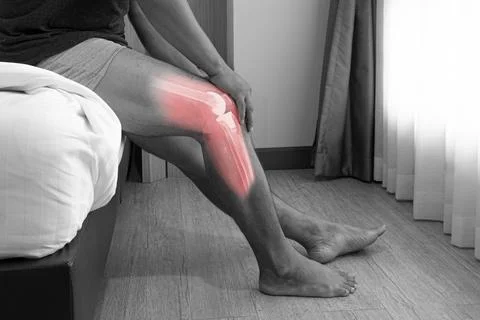 Close up a man siting on the bed and holding his knee pain Joint pain after p Stock Photos