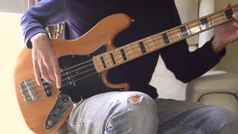 Close-up of man sitting and playing vintage electric bass guitar at home. Unr Stock Footage 164721881