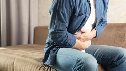 Close-up of a man sitting on the couch, suffering from abdominal pain Stock Footage 270730235