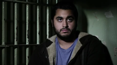 Close up of man sitting in dark jail cell Stock Footage 191353472