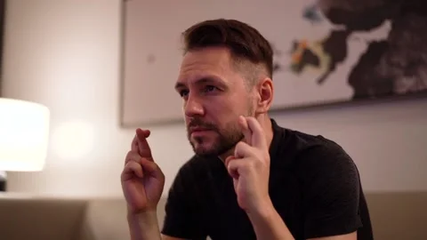 Close up of man sitting in front of TV with fingers crossed Stock Footage 221263742