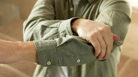 Close-up of man sitting on sofa doing massage on elbow with hand Video stock 270729680