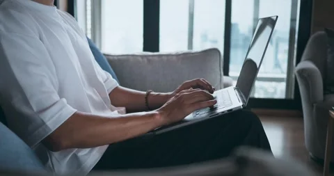 Close-up man sitting on sofa in home and using laptop at home. Closeup of a man Stock Footage 252215304