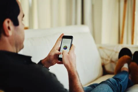 Close-up of a man sitting on sofa using smartphone Stock Photos