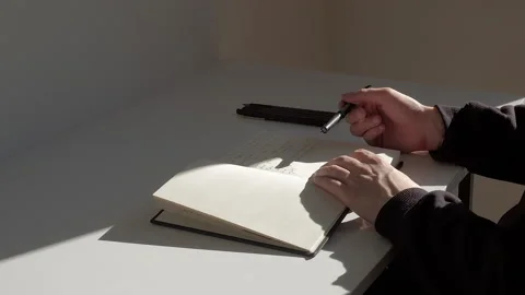 Close-up: man sitting at the table and tapping a pen on the white page of diary Stock Footage 229896319