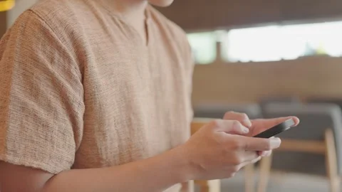 Close-up of a man sitting typing messages on a smartphone and surfing Stock Footage 251974243