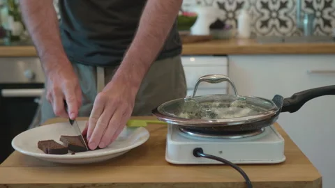 Close-up of a man slicing dark rye bread on a white plate Video stock 325222689