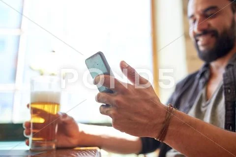 Close up of man with smartphone and beer at pub Stock Photos