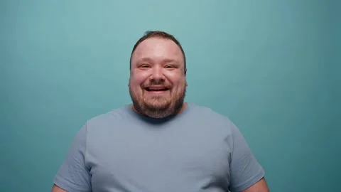 Close-up of a man smiling at camera on a blue background Видео 237549616