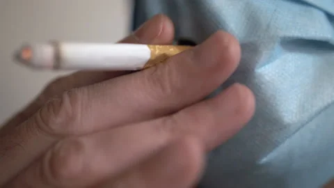 Close up of a man smoking a cigarette through a hole in a face mask 스톡 동영상 132900246