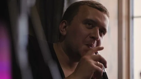 Close-up of a man Smoking a hookah in a cafe near a large window. Stock Footage 106328770