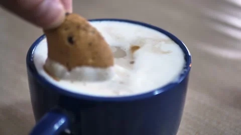Close up of a man soaking chocolate chip cookies in cappuccino Stock Footage 148142842