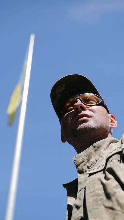 Close-up of man soldier standing under the large blue and yellow Ukrainian flag Stock Footage 277134259