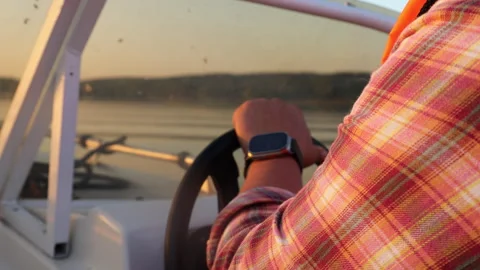 Close-up of a man spinning the steering wheel of a boat Stock Footage 283489033