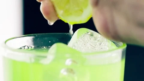 Close-up of man squeeze yellow lemon on drink alcohol cocktail into the glass Stock Footage 79147087