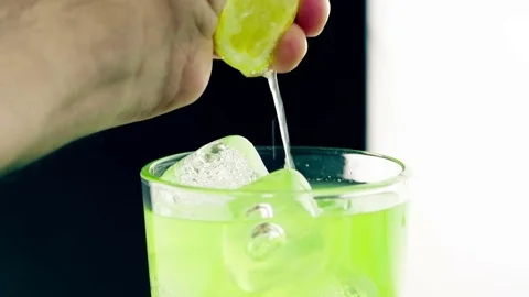Close-up of man squeeze yellow lemon on drink alcohol cocktail into the glass 스톡 동영상 80004361
