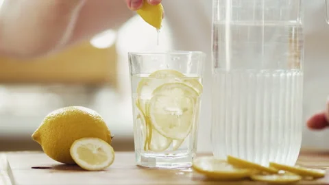 Close Up of Man Squeezing Fresh Lemon Slice into Glass of Water 4K 10-bit	 Stock Footage 332680291