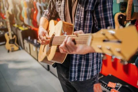Close up of man standing and playing on acoustic guitar. He dresses up like Stock Photos