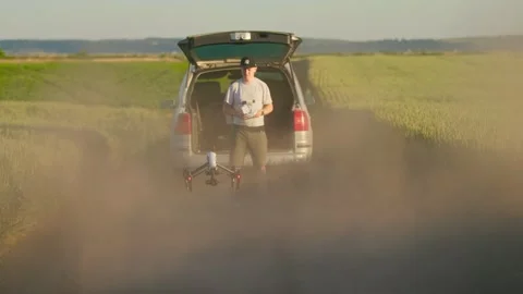 Close up man standing remote control drone in a field near the car. Drone flying Stock Footage 202986045