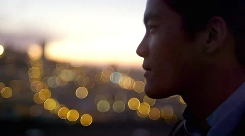 Close up of a man standing on a roof drinking a cocktail at sunset with the city Stock Footage 44108903
