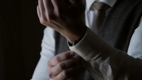 Close-up of a man standing by a window straightens the cuffs of his shirt and Stock Footage 302285029